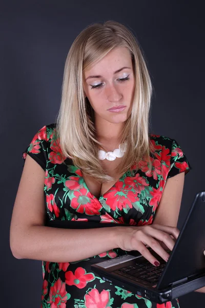 Portret van de mooie blonde met laptop op een zwarte achtergrond — Stockfoto