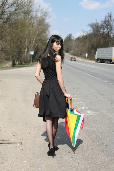 Girl with umbrella on the road — Stock Photo, Image