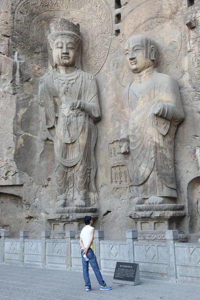 Un uomo che guarda vecchie sculture. Grotte della porta dei draghi — Foto Stock