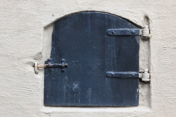 Historical old closed metal window shutter in rough wall — Stock Photo, Image