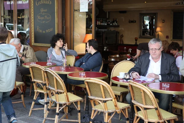 PARÍS - 27 DE ABRIL: Los parisinos y los turistas disfrutan de comidas y bebidas en la acera de la cafetería en París, Francia, el 27 de abril de 2013. París es una de las áreas metropolitanas más pobladas de Europa . — Foto de Stock