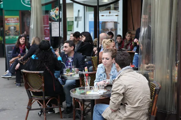 PARIS - 27 de abril: Parisienses e turistas gostam de comer e beber na calçada do café em Paris, França, em 27 de abril de 2013. Paris é uma das áreas metropolitanas mais povoadas da Europa . — Fotografia de Stock