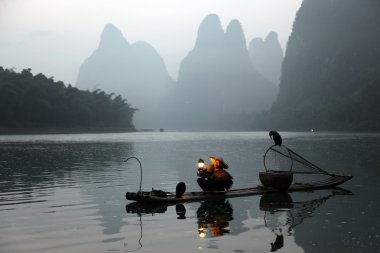 Yangshuo - 18 Haziran: Çinli adam karabatak kuşlar yangshuo, guangxi bölge, geleneksel balıkçılık kullanımı ile Balık tutma eğitimli karabatak balık için 18 Haziran 2012 yangshuo içinde guangxi, china