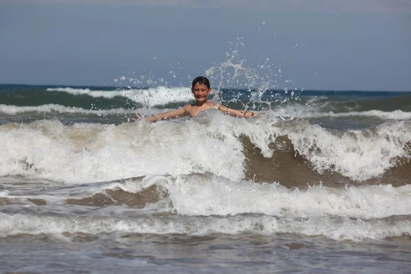Ragazzo giocare con le onde dell'oceano — Foto Stock