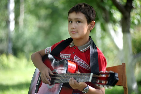 Jongen gitaarspelen buitenshuis — Stockfoto