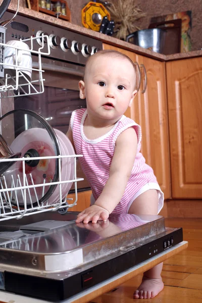 Child 1 year old in the kitchen at dishwasher — Stock Photo, Image