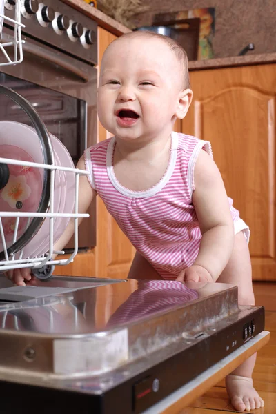 Funny child 1 year old in the kitchen at dishwasher — Stock Photo, Image