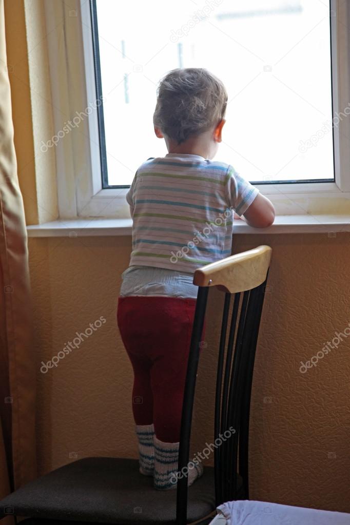 alone little boy looking in window
