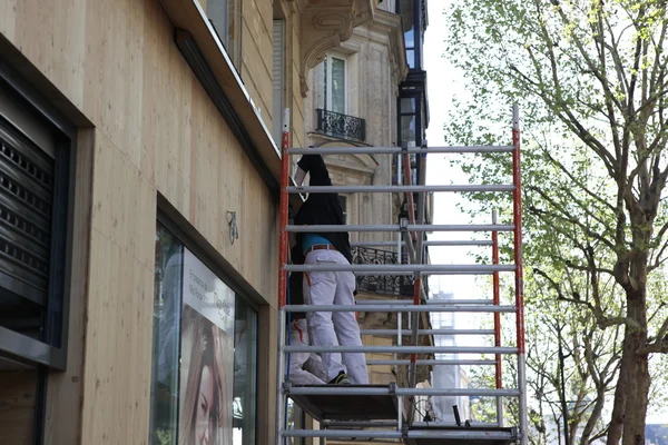 Строители, устанавливающие плитку на фасад здания — стоковое фото