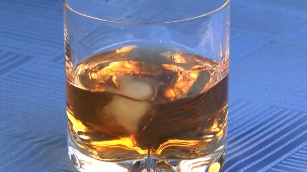 Ijs toevoeging in whisky. — Stockvideo