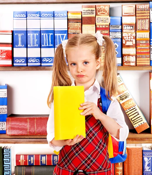 Kind met boek op boekenplank. — Stockfoto