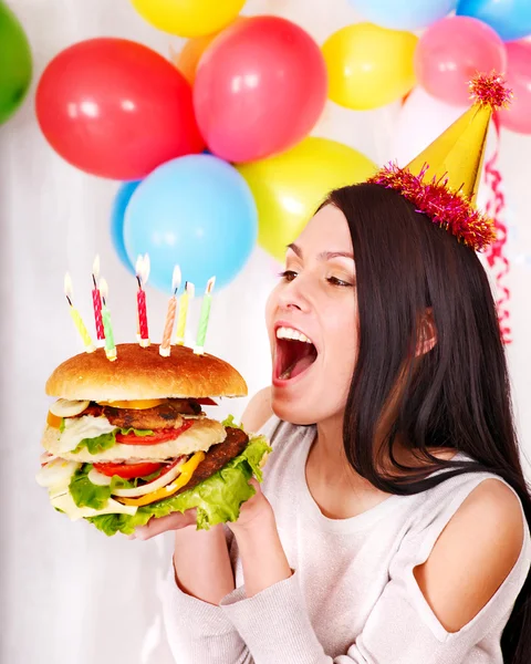 Woman eating hamburger at birthday. Stock Picture