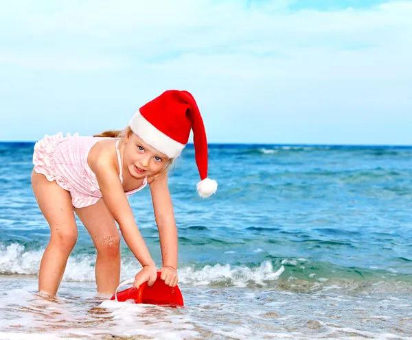 Criança em santa chapéu brincando na praia . — Fotografia de Stock