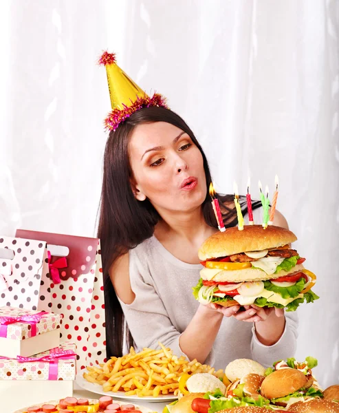 Woman eating hamburger at birthday. Stock Image