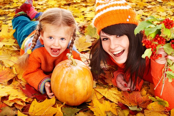 Familia feliz con calabaza en hojas de otoño . — Foto de Stock