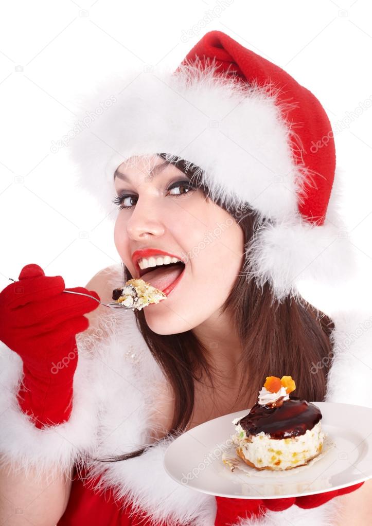 Christmas girl in santa hat and cake on plate.