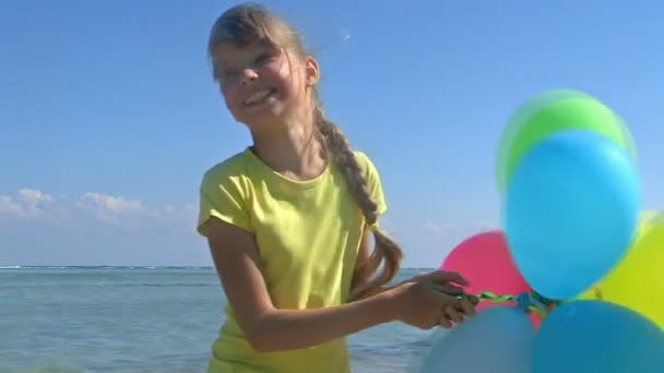 Child playing with balloons at the beach — Stock Video