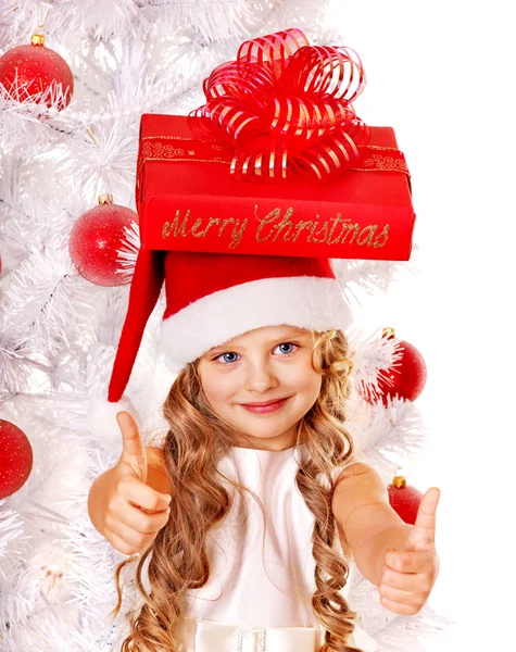 Kind in Kerstman hoed met de doos van de gift in de buurt van witte kerstboom. — Stockfoto