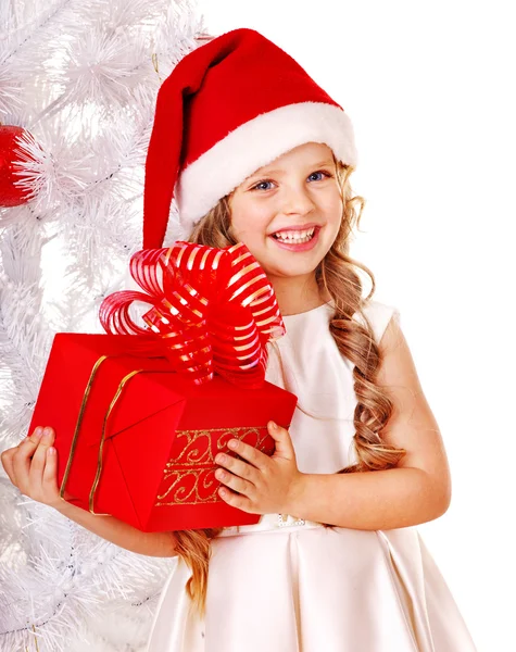 Kind in Weihnachtsmütze mit Geschenkbox neben weißem Weihnachtsbaum. — Stockfoto