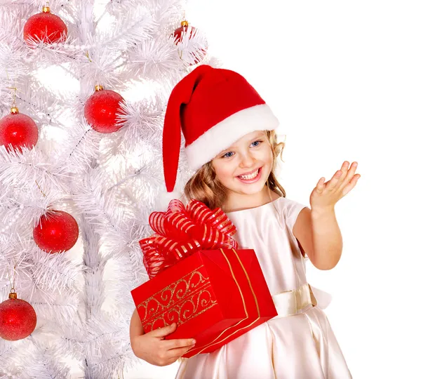 Enfant en chapeau de Père Noël avec boîte cadeau près de l'arbre de Noël blanc . — Photo