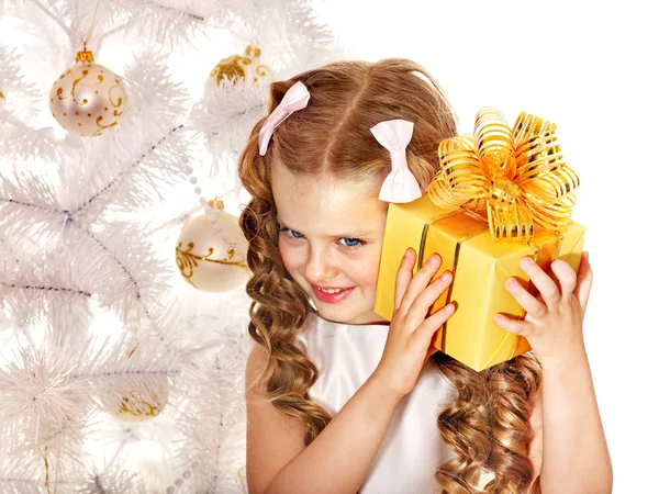 Child with gift box near white Christmas tree. Stock Picture