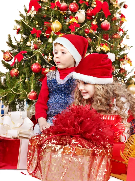 Kinder in Weihnachtsmütze mit Geschenkbox in der Nähe des Weihnachtsbaums. — Stockfoto