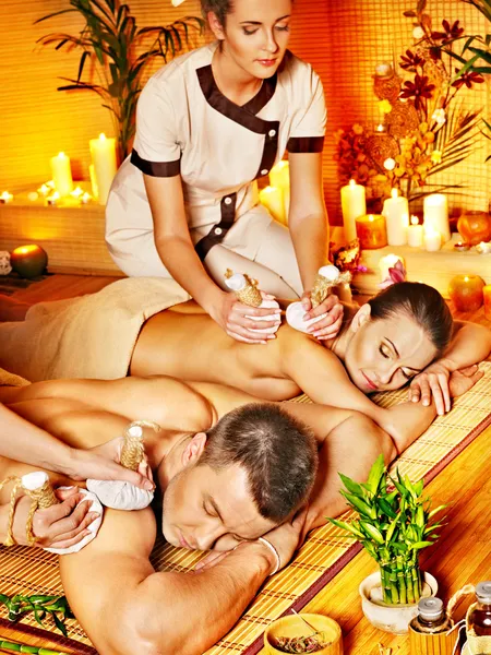 Mann und Frau bekommen Kräuterball-Massage im Wellnessbereich. — Stockfoto