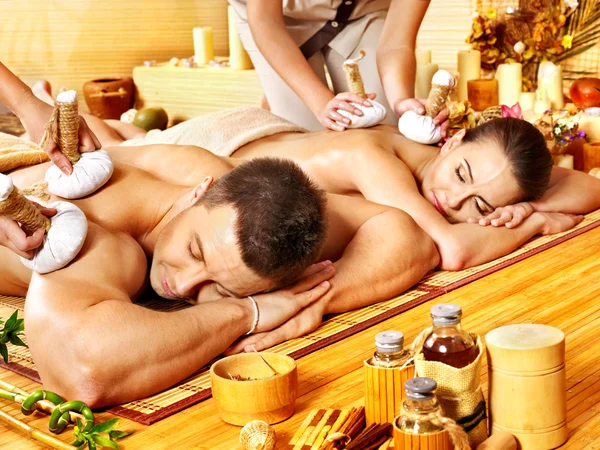 Mann und Frau bekommen Kräuterball-Massage im Wellnessbereich. — Stockfoto
