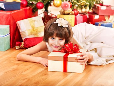 Çocuk Noel ağacının yanında hediye kutusu.