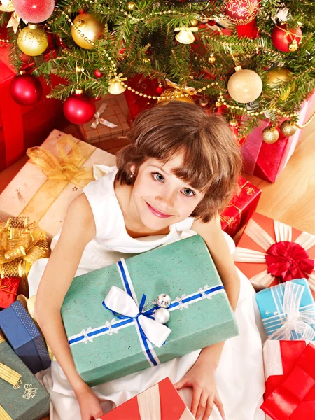 Child with gift box near Christmas tree. Stock Photo