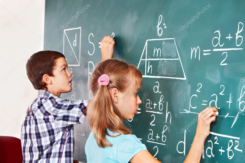 School child writting on blackboard.
