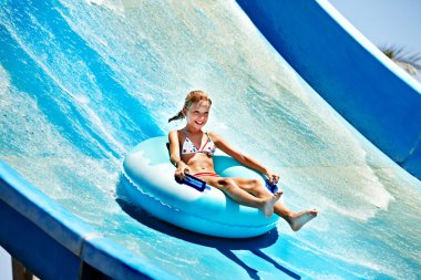 Child on water slide at aquapark. clipart