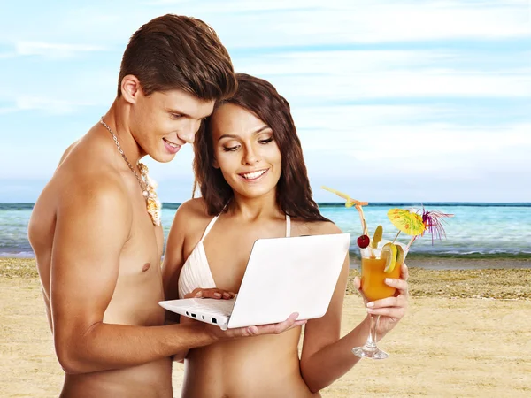 Pareja con portátil en la playa . — Foto de Stock