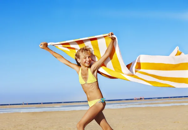 Dziecko działa na plaży z ręcznikiem. — Zdjęcie stockowe
