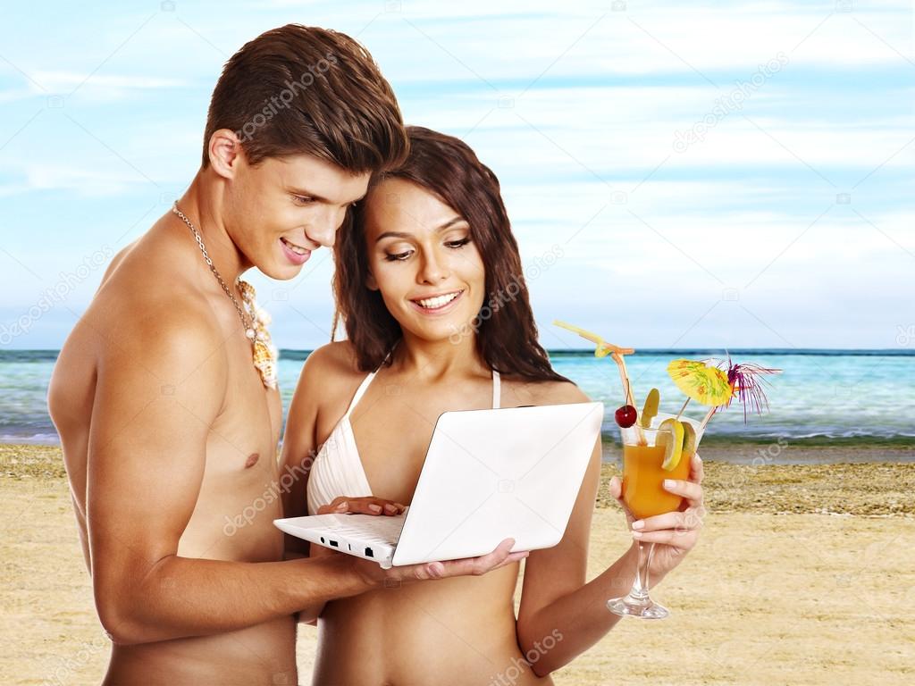 Couple with laptop at beach.