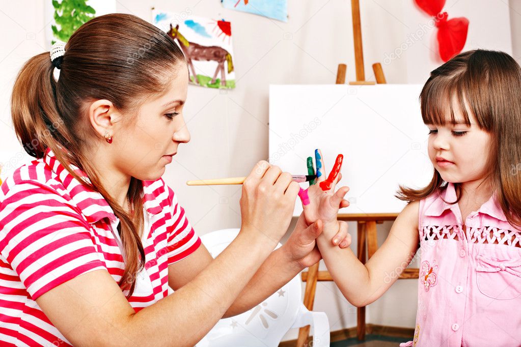 Child painting with teacher in preschool.