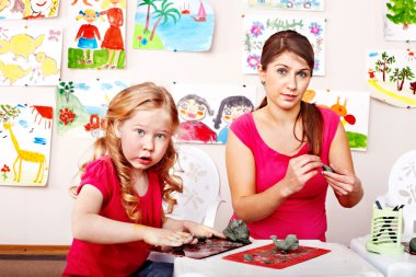 Teacher and kid playing with clay. clipart