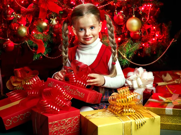 Kind mit Geschenkbox in der Nähe des Weihnachtsbaums. — Stockfoto