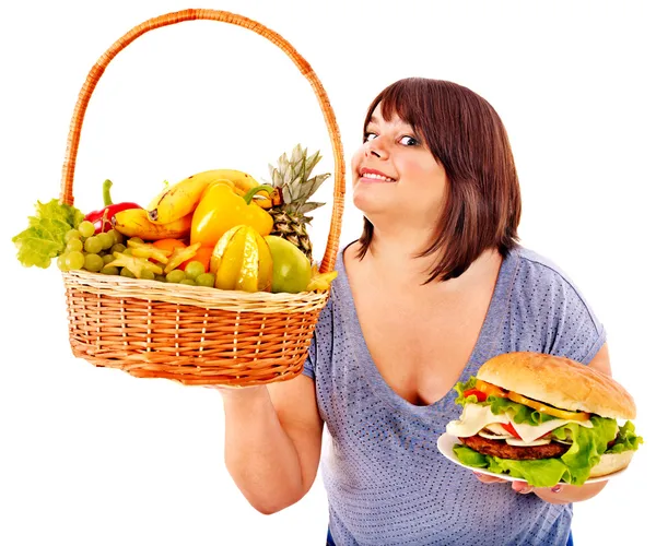 Mujer eligiendo entre fruta y hamburguesa . — Foto de Stock