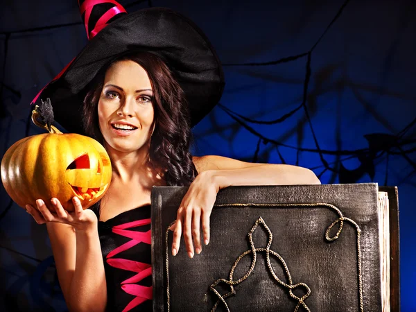 Witch woman holding old book and pumpkin — Stock Photo, Image