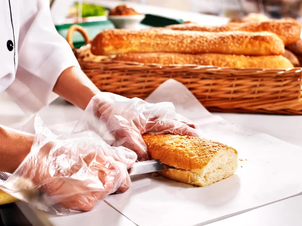 Female hand cutting baguette. — Stock Photo, Image