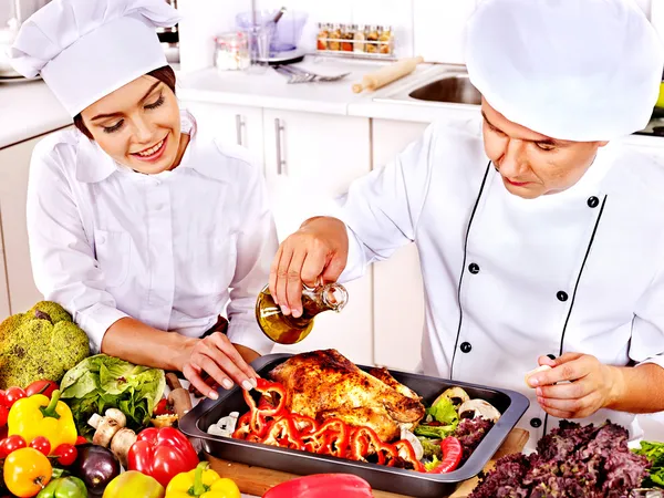 Homem e mulher em chapéu de chef cozinhar frango — Fotografia de Stock