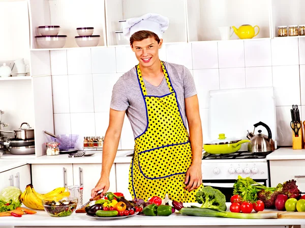 Muž v klobouku šéfkuchaře vaření v kuchyni. — Stock fotografie