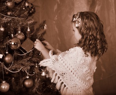 Çocuk Noel ağacı üzerinde mum tutuşturan.