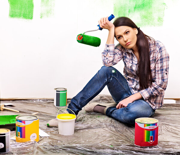 Woman paint wall at home.