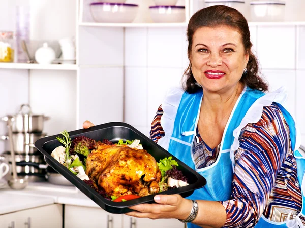 Mulher madura preparando frango na cozinha . — Fotografia de Stock