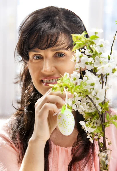 Mujer colgar huevo de Pascua en rama de cereza . — Foto de Stock
