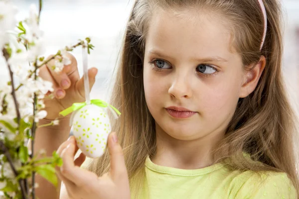 Kind hang easter egg op cherry branch. — Stockfoto