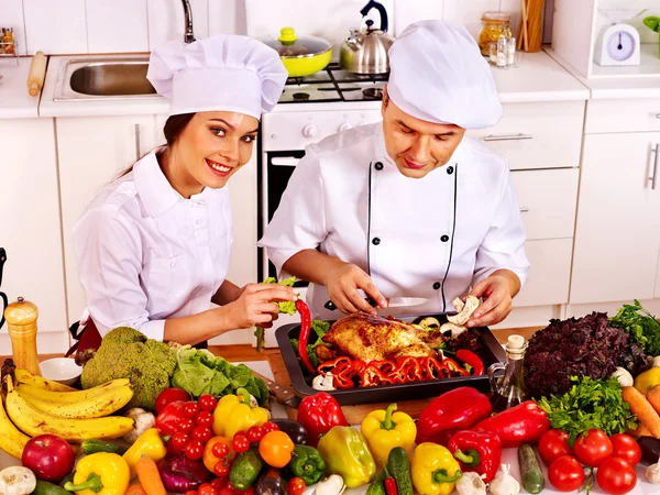 Mężczyzna i kobieta w kapeluszu szefa kuchni, gotowania kurczaka — Zdjęcie stockowe