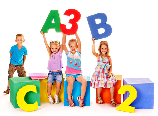 Children sitting at cube and holding letters